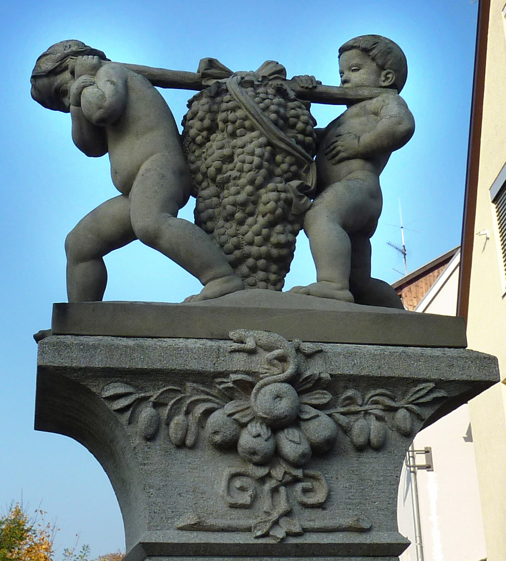 steinerne Brunnenfigur aus zwei Knaben, die eine riesige Weinrebe tragen